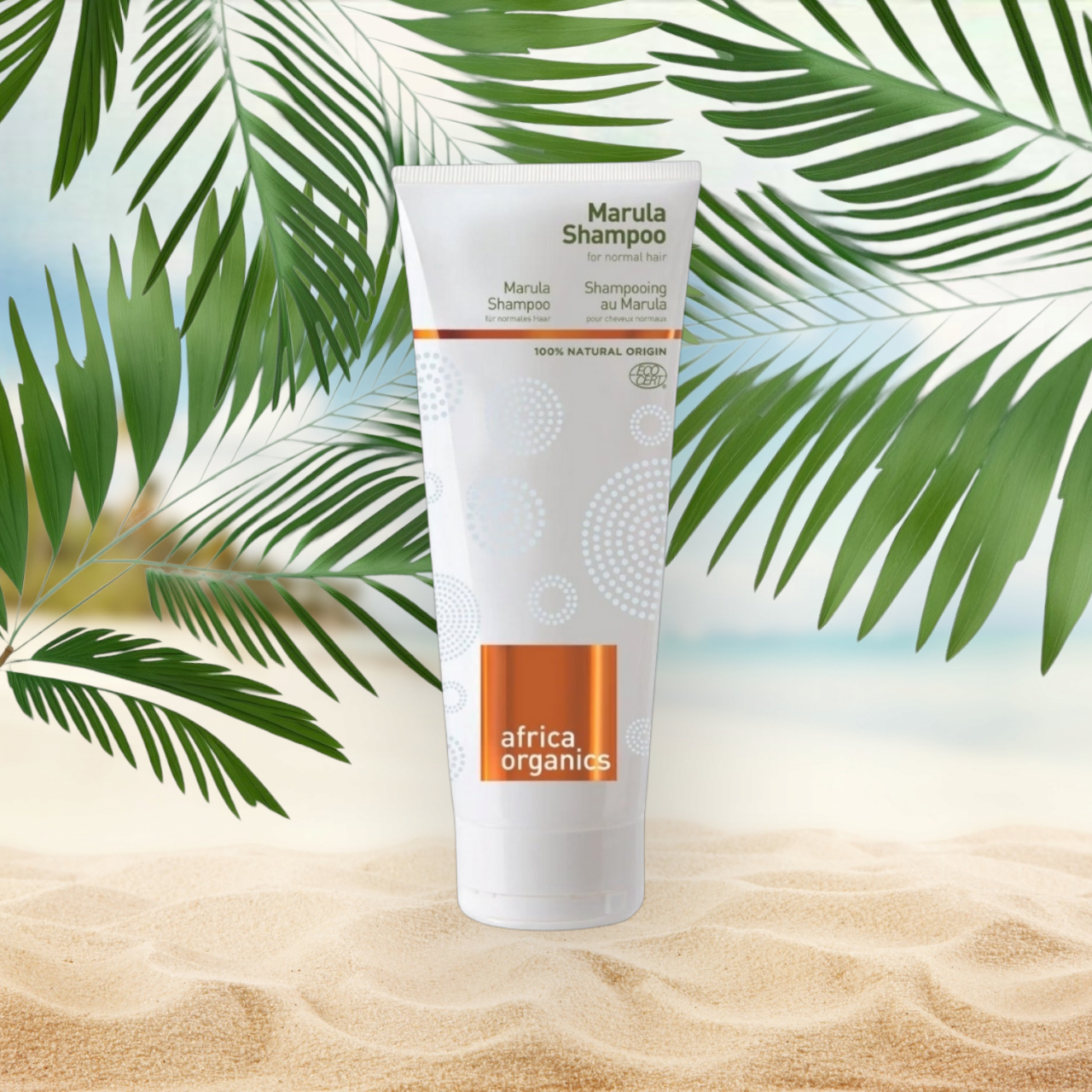 En tube Africa Organics Marula shampoo 210ml på en strand med palmeblade.