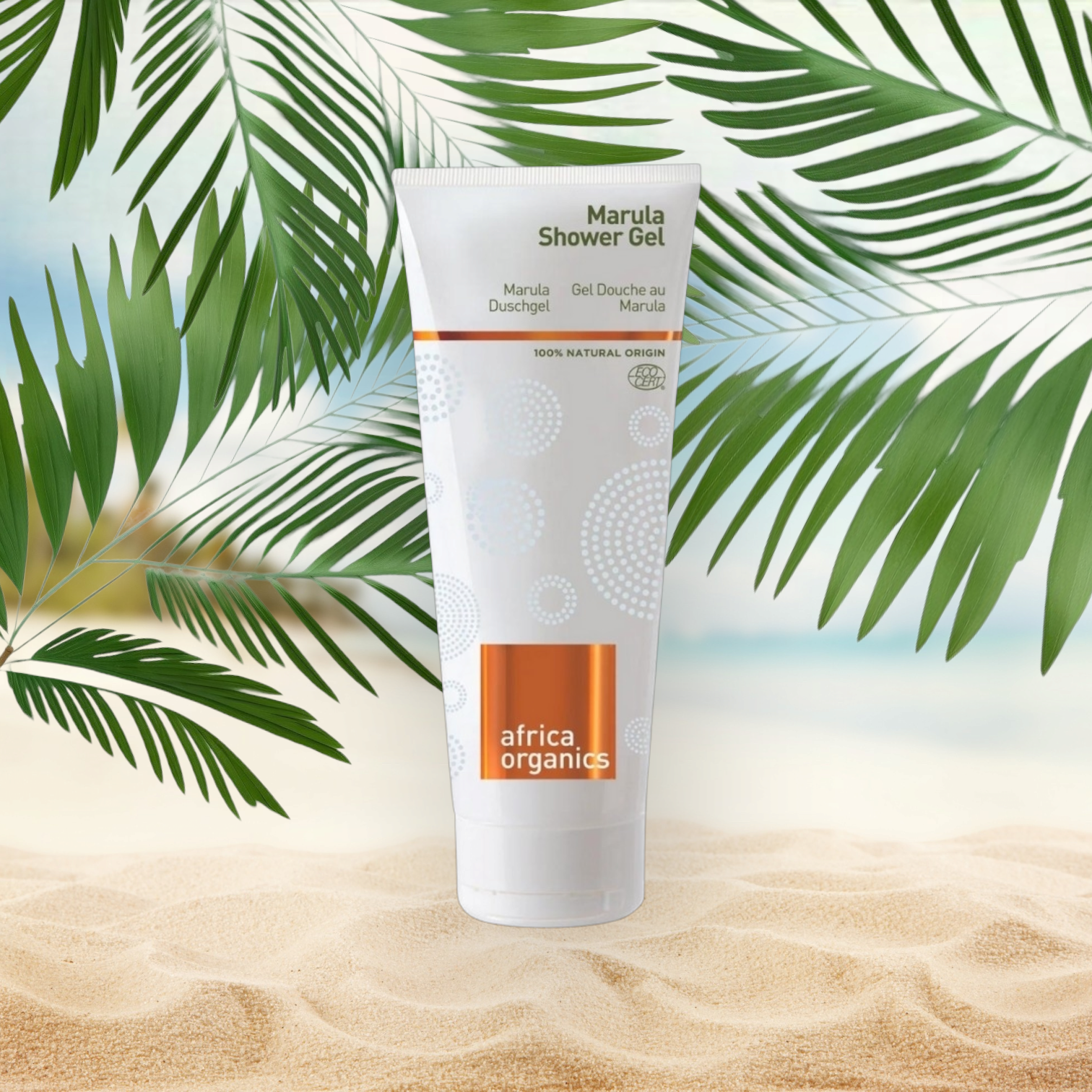 Pureday En tube Africa Organics Marula shower gel 210ml, med naturlige ingredienser, placeret på en sandstrand baggrund med tropiske palmeblade, der ligger lidt over toppen.