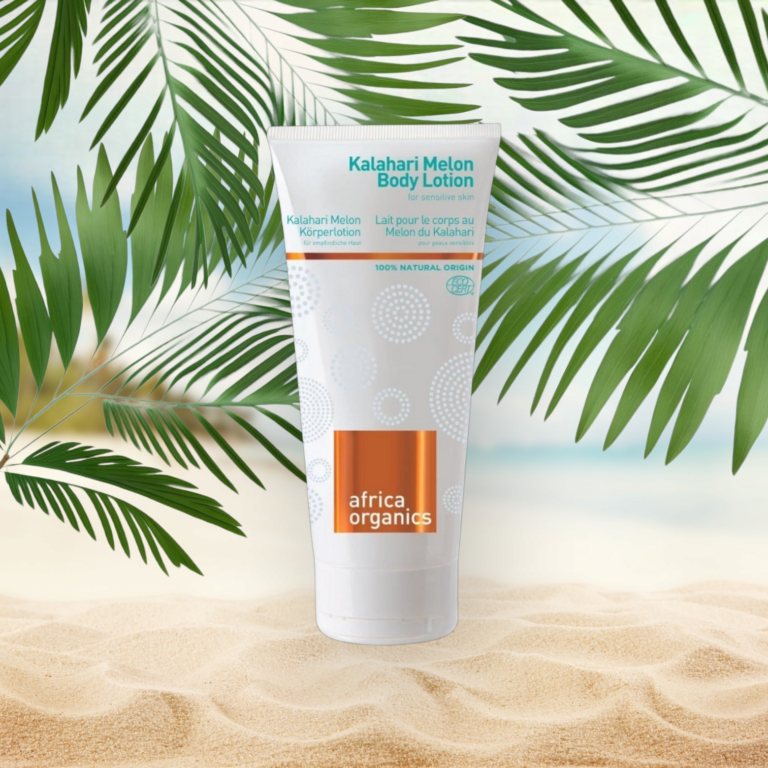 Pureday En tube Africa Organics Kalahari Melon Body Lotion 200 ml fra Matas står på en sandstrand baggrund, flankeret af grønne palmeblade med en klar, solrig himmel.