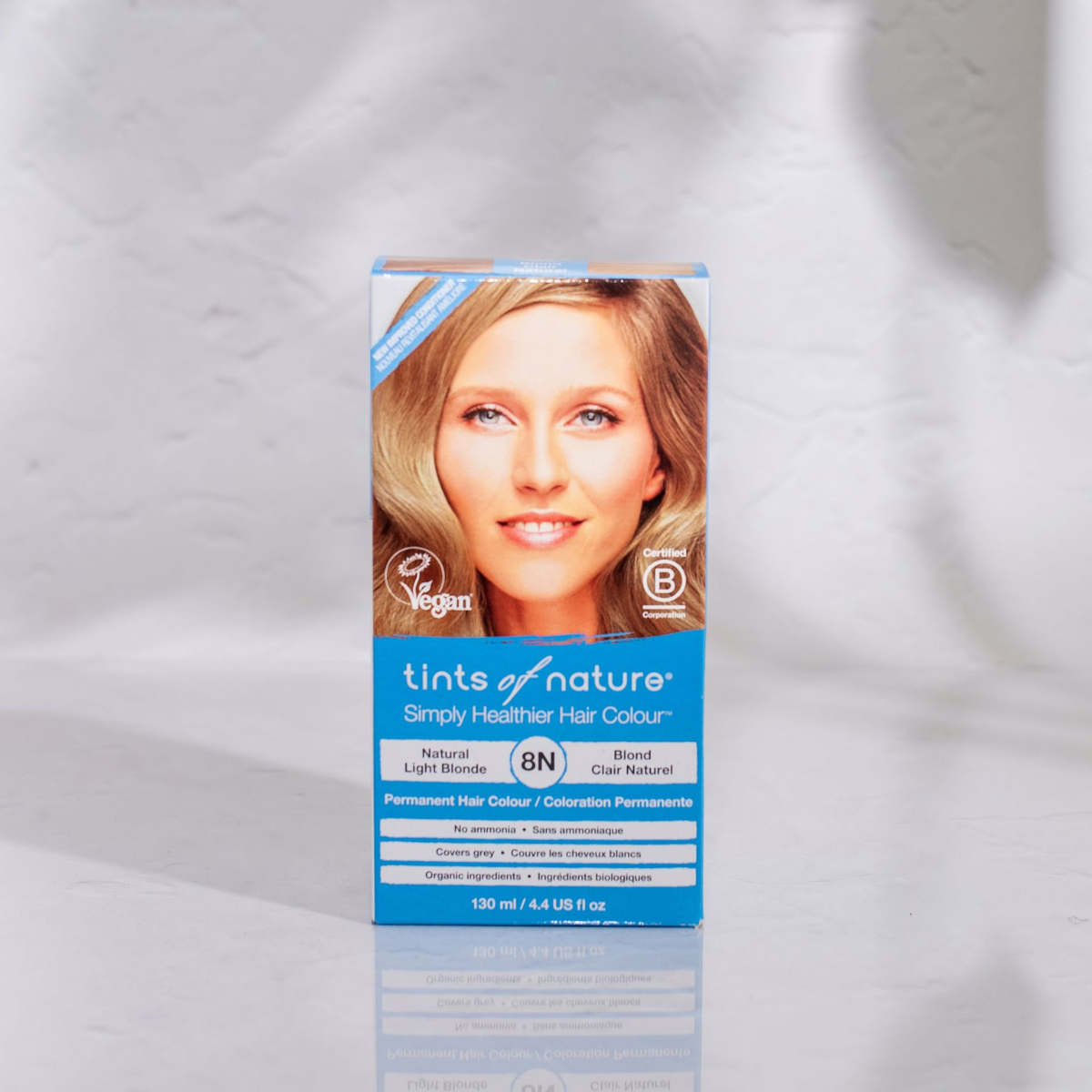 En Økologisk hårfarve - Tints of Nature 8N Light Blonde 130 ml æske med et kvindeansigt på, der fremmer helbred og velvære.