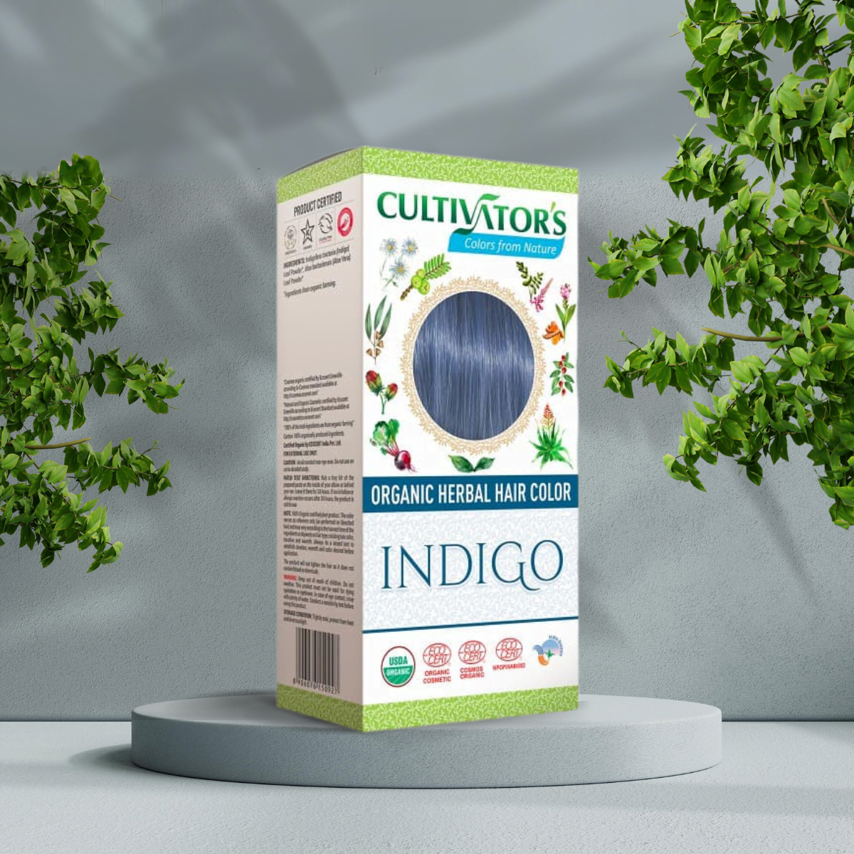 Pureday En kasse med Cultivators Indigo 100g økologisk urte-hårfarve vist på et cirkulært stativ, omgivet af grønne planter, mod en neutral Pureday-baggrund.