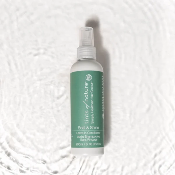 Pureday En grøn flaske Tints of Nature Seal & Shine leave-in shampoo 250ml liggende på en struktureret hvid baggrund. Etiketten viser produktdetaljer inklusive kapacitet (200ml/6,76 US fl oz) og ø