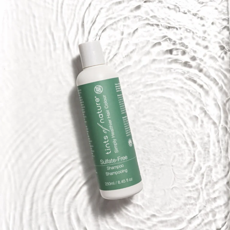 Pureday En flaske frisk Tints of Nature Sulfate fri shampoo 250ml på en tekstureret hvid overflade, der efterligner udseendet af flydende, bølget creme, der understreger produktets rene og naturlige æstetik.