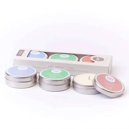 Pureday Fire små, runde bliklys med farverige etiketter i en Soylites 3 Pack Gavesæt pappakke, illustreret mod en almindelig hvid baggrund. Etiketterne har forskellige dufte og farver.
