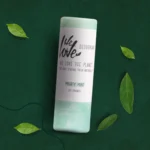 En tube Økologisk deodorantstift - Mighty Mint 65g med naturlige grønne blade omkring.