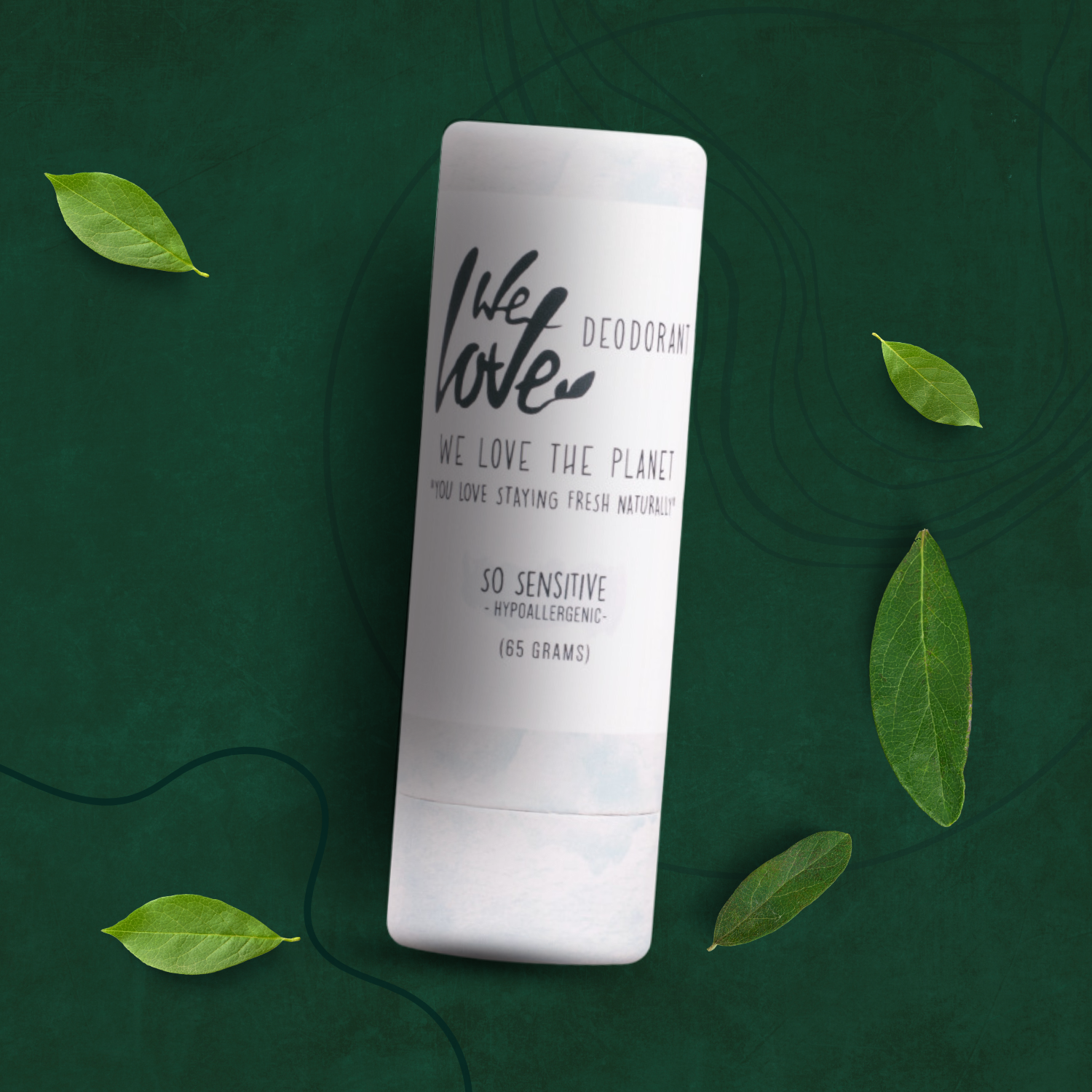 En naturlig tube af Økologisk deodorantstift - So Sensitive 65g med grønne blade omkring, der fremmer helbred og velvære.