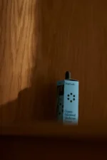 Pureday En flaske Kosttilskud reishi - Svampe Ekstrakt - Øko af Mind Studio hviler på en varm træbaggrund, fremhævet af blødt, naturligt lys, der kaster en skygge.